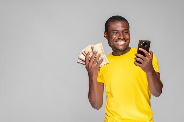 Excited young black man holding money using his phone